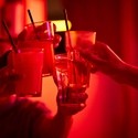 Cropped image of male and female friends toasting drink glasses at bowling alley.