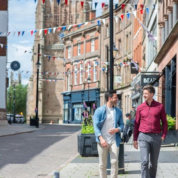 Two men walking past shops and restaurants
