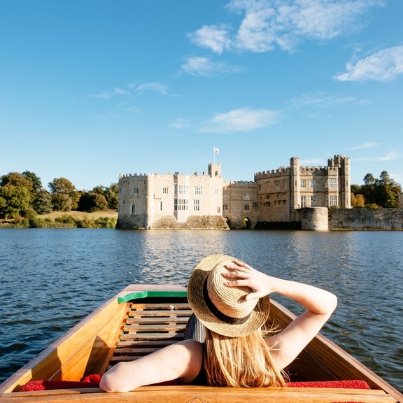 Woman in a punt on the moat looking towards castle