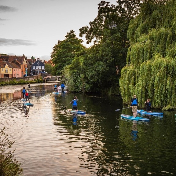 A group of people paddleboarding on the River Wensum