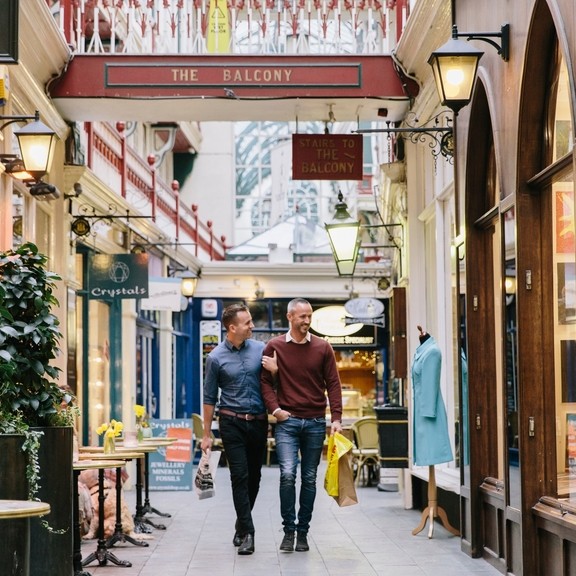 A gay couple, with arms linked, shopping indoors