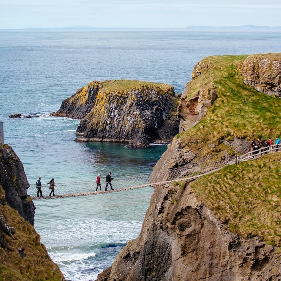 Distant view of people crossing a rope bridge over the sea