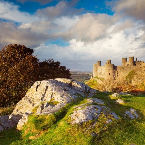 Harlech Castle standing on a grassy hilltop in North Wales. Blue skies and clouds