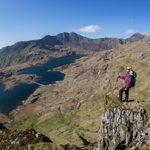 Woman standing on a rock, high above the lake in a valley