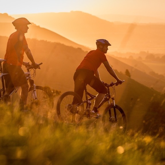 Two men on mountain bikes cycling at Devil's Dyke. Sunrise