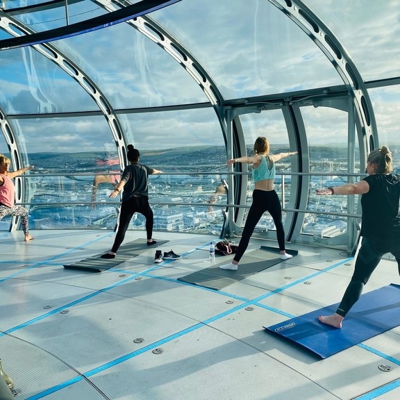 Female yoga class taking place on the viewing platform of British Airways i360 Viewing Tower, Brighton, East Sussex, England