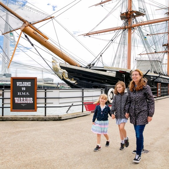 A family walking alongside a ship at a dock