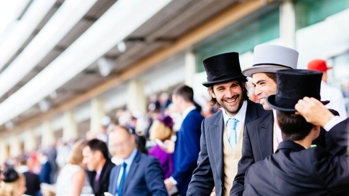 Men dressed in morning suits and top hats watching a race