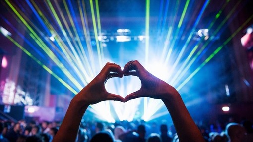 Woman making heart shape with hands at music event. UK