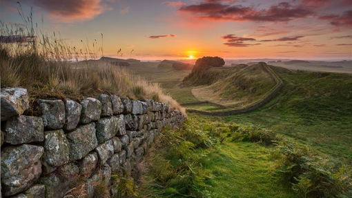 View along long stone wall over the fields at sunset