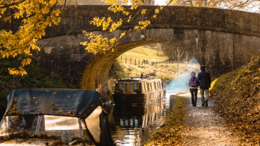 Man and woman walking beside a canal near a low bridge