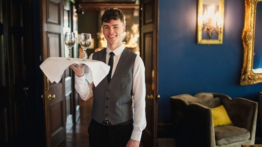 Waiter holding a tray with wine and smiling towards the camera