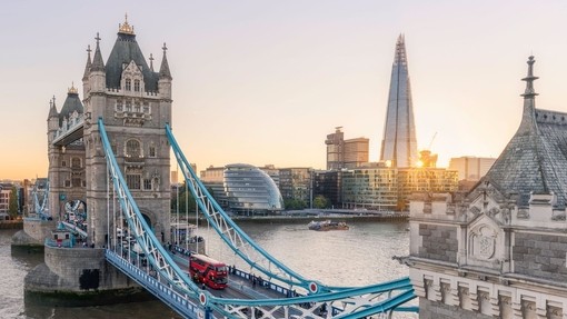 View of Tower Bridge and Shard at sunset, with a red bus going across it