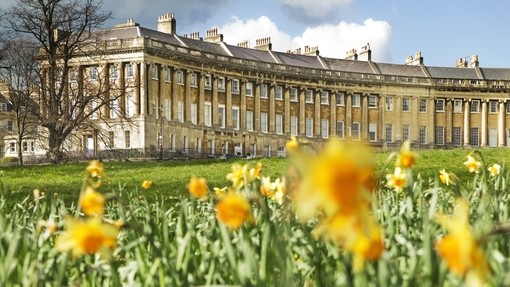 External view of regency style building of the Royal Crescent, Bath through a field of blurred out daffodils in the foreground,