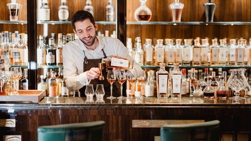 A bartender pouring whisky into glasses.