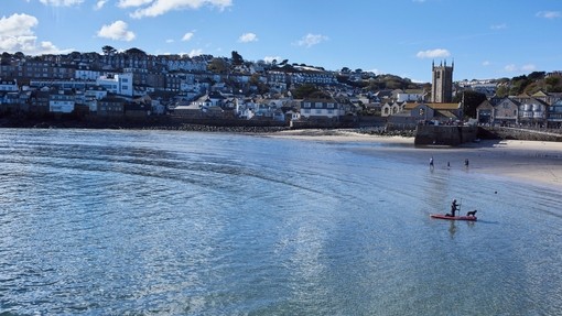 Distant view of town and harbour with people in the sea