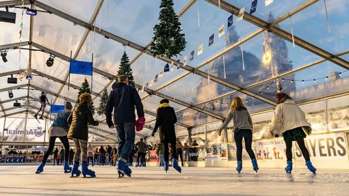 People ice skating on a skating rink under glass ceiling