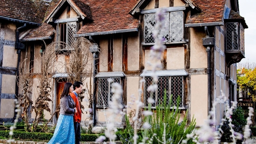 Couple walking through a garden of a Tudor building