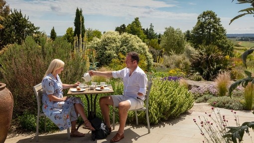 A man and a woman having afternoon tea in a garden in the summer