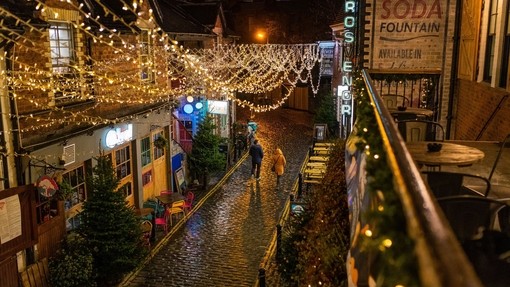 Rows of fairy lights draped over a cobbled street at night