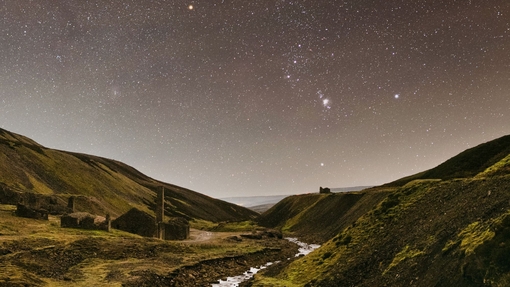 A stream winding through the mountains under a starry sky.