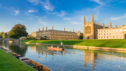 People punting along a river next to a college and chapel.