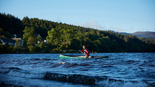 Man canoeing on a lake on a clear sunny day.