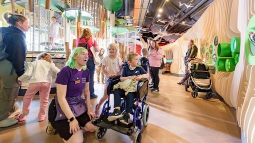 Inside a Science & Discovery Centre with children, including one wheelchair user and staff member.