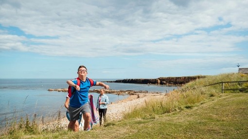 A young boy with Downs Syndrome playing on the beach