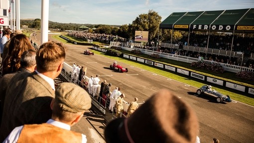 Spectators watching a motor race of vintage sports cars