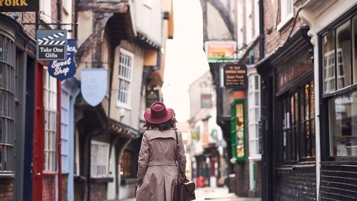 Woman wearing trench coat and pink hat walking
