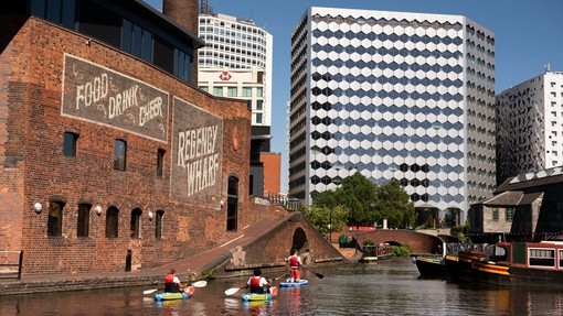 A group of people paddleboarding past the Regency Wharf in Birmingham.