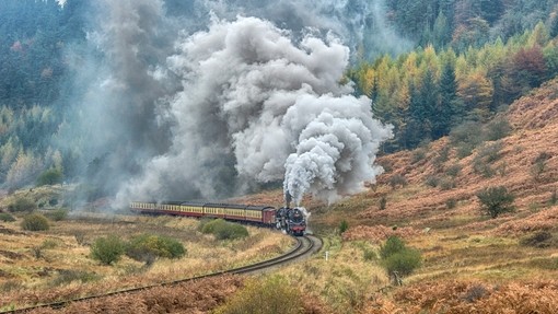 A steam train on North Yorkshire Moors Railway billowing clouds of smoke, Yorkshire, England.