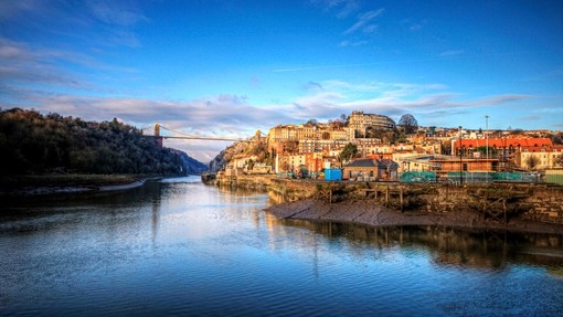 Bristol seen from the river with Clifton Suspension Bridge in background against a blue sky