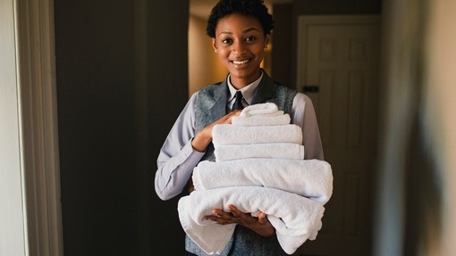 Hotel employee carrying pile of fresh towels for a hotel room