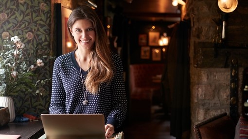 Female receptionist smiling at the camera working on laptop at Hotel check in