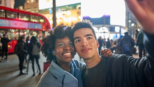Young couple taking a selfie in the evening at Piccadilly Circus, London