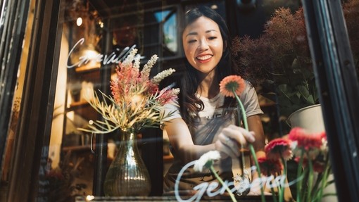 Asian young florist working on the arrangement of flowers for her shop.