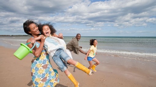 Family playing on the beach in the sunshine, Northumberland