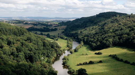Landscape view of river winding through green fields and hills in the countryside