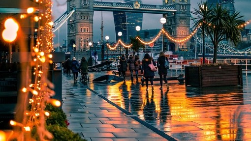 People walking past fairy lights on a city street at night