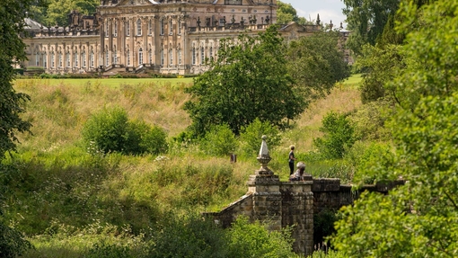 Large country house surrounded by trees with stream in the foreground
