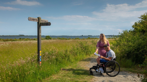 A man who uses a wheelchair and a woman review a map in the countryside