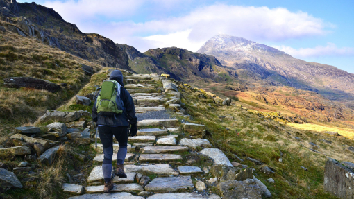 Trekker hiking up a mountainous cobble stoned path through a barren mountain range