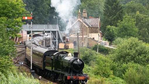 Locomotive 2857 pulling a series of carriages leaving the heritage station