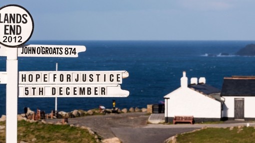 White painted signpost on a clifftop at Lands End. White building