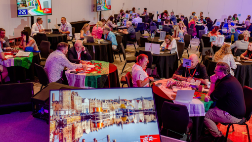 A room filled with attendees sat at tables at a business event