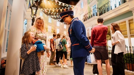 Character actors talking to a young child on the set of a stage.