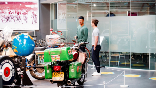 Two men looking at an exhibit of motorbikes in a museum.