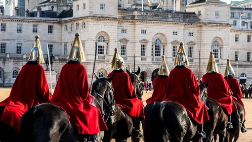 Horse Guards wearing red coats riding across parade